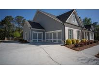 Charming home features a three-car garage and a well-maintained lawn, and brick accents at 6165 Namon Wallace Dr, Cumming, GA 30028