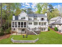 A sprawling white home featuring a screened porch and lush green lawn with trees in the background at 1141 Ragley Hall Ne Rd, Brookhaven, GA 30319