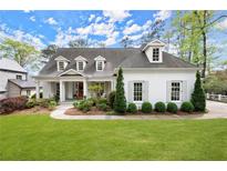 Charming white brick home featuring a manicured lawn, covered porch, and dormer windows at 1141 Ragley Hall Ne Rd, Brookhaven, GA 30319