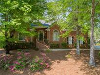 Charming brick home featuring a well-manicured lawn, mature trees, and welcoming front porch at 225 Wexford Overlook Dr, Roswell, GA 30075