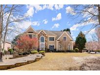 Charming two-story home featuring a stone facade, manicured lawn, and mature landscaping at 300 Morganshire Pl, Atlanta, GA 30350