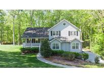 Charming two-story home with a welcoming front porch and well-manicured lawn surrounded by mature trees at 619 Stoney Creek Rd, Woodstock, GA 30188