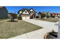 Two-story brick home features a two-car garage, landscaped yard, and a long concrete driveway at 2030 Hydrangea Ln, Austell, GA 30106