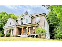 Charming two-story brick home with a welcoming front porch and lush landscaping at 2870 Willow Wisp Way, Cumming, GA 30040