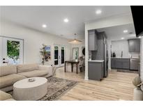 A bright open-concept living area features wood floors, a modern couch, and an open view into the dining and kitchen spaces at 5250 Chemin De Vie, Atlanta, GA 30342