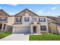 Charming two-story home featuring a brick facade, attached garage, and well-manicured lawn at 7554 Crawford Ct, Fairburn, GA 30213