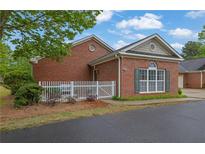 Charming brick home featuring a white picket fence and manicured landscaping at 509 Sawnee Corners Dr, Cumming, GA 30040