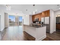 Modern kitchen featuring an island, stainless steel appliances, and dark hardwood floors, bathed in natural light and open to skyline views at 1080 Peachtree Ne St # 2515, Atlanta, GA 30309