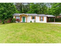 Charming home with a bright green front door and a covered carport, surrounded by a lush lawn at 2804 Hall Se Dr, Smyrna, GA 30082