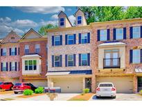 Charming brick townhome with a two-car garage and well-maintained landscaping and blue shutters at 2919 Camplay Dr, Suwanee, GA 30024