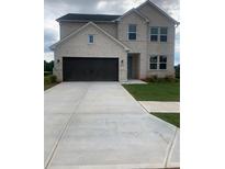 Two-story brick home featuring a dark garage door, neatly kept lawn and gray cloudy skies at 129 Kenney Way, Locust Grove, GA 30248