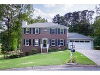 Charming two-story brick home with black shutters, a green lawn, and a two-car garage at 5083 Lambeth Nw Ct, Acworth, GA 30101