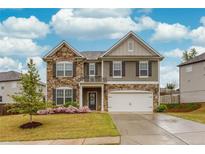 Charming two-story home featuring a stone and gray siding exterior, lush landscaping, and a two-car garage at 637 Little Bear Loop, Canton, GA 30114