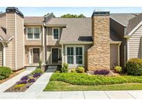 Charming townhome featuring a stone chimney, manicured lawn, and inviting walkway at 1420 Defoors Nw Dr, Atlanta, GA 30318