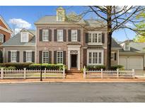 Charming two-story brick home featuring a white picket fence, shutters, and manicured landscaping at 1128 Bellewood Sq, Dunwoody, GA 30338