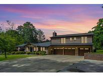 Stunning brick home featuring a three-car garage and lush landscaping against a colorful sunset backdrop at 204 Mt Moriah Rd, Auburn, GA 30011