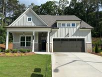 Charming home showcasing a two-car garage, green lawn, and inviting front porch at 3032 Farm Tract Trl, Woodstock, GA 30189