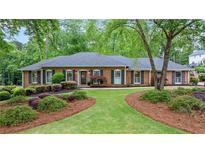 Charming single-story brick home featuring lush landscaping, a well-manicured lawn, and black shutters at 1405 Murdock Rd, Marietta, GA 30062