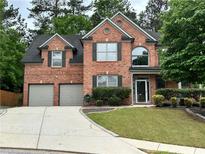 Traditional brick home with a two-car garage, manicured lawn, and mature landscaping in a suburban setting at 1425 Bridle Path Dr, Lawrenceville, GA 30045