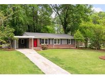 Charming single-story home with brick accents, a covered carport, a well-manicured lawn and a red front door at 3007 Stratford Arms Dr, Chamblee, GA 30341