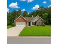 Charming one-story home with a well-manicured lawn, brick facade, and attached garage at 1220 Skipping Rock Sw Ln, Grayson, GA 30017