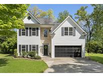 Charming two-story home with white siding, stone accents, a manicured lawn, and a two-car garage at 429 Tannenhill Pl, Sugar Hill, GA 30518