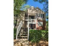 Two-story condo featuring brick accents, wood siding, a front porch, and staircase entrance surrounded by lush landscaping at 446 Teal Ct, Roswell, GA 30076