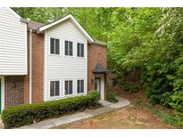 Charming townhome featuring brick accents, white siding, and lush landscaping in a serene wooded setting at 7098 Stonington Dr, Atlanta, GA 30328