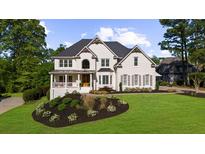 Stunning white painted brick two-story home with manicured lawn and beautiful landscape design at 7390 Canter Run, Cumming, GA 30040
