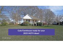 Charming single-story farmhouse featuring a cozy front porch and beautiful, established landscaping at 2651 Old Lost Mountain Rd, Powder Springs, GA 30127