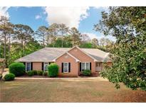 Charming brick ranch with well-manicured lawn, mature trees, and inviting front entrance at 1030 E Lakehaven Way, Mcdonough, GA 30253