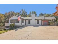 Charming one-story home featuring a covered carport, a brick chimney and a long cracked driveway at 6684 Birch Rd, Winston, GA 30187