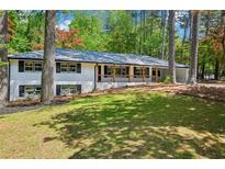 Charming painted brick home featuring a front porch and a beautifully landscaped front yard at 2301 Crestcliff Dr, Tucker, GA 30084