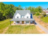 Stunning two-story home with a classic farmhouse design and welcoming front porch with rocking chairs at 5315 Hendrix Rd, Cumming, GA 30040