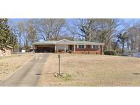 Cozy single-story brick home with a covered carport and a spacious front yard on a sunny day at 6073 Terry Ln, Austell, GA 30168