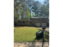 Charming single-Gathering home featuring brick facade, arched front windows, two-car garage, and a spacious front yard with mature trees at 1001 Woodbridge Ne Way, Conyers, GA 30012