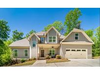 Charming two-story home features an attached two-car garage, and inviting covered entryway with rocking chairs at 2025 Goldmine Dr, Cumming, GA 30040