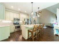 Eat-in kitchen features an island with bar seating, stainless appliances, and lovely pendant lighting at 2025 Goldmine Dr, Cumming, GA 30040
