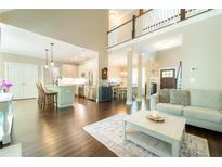 Bright open-concept living room with hardwood floors, high ceilings, and a modern kitchen in the background at 2025 Goldmine Dr, Cumming, GA 30040