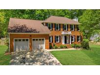 Traditional brick home featuring a two-car garage, manicured lawn, and charming architectural details at 2700 Sandstone Dr, Lawrenceville, GA 30043