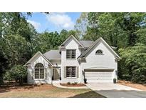 Charming two-story painted brick home with a well-manicured lawn and mature trees at 1725 Redbud Way, Cumming, GA 30041