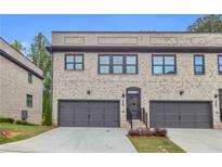 Charming townhome featuring a gray brick facade, a two-car garage, and a well-maintained lawn at 3493 Monarch Ave, Duluth, GA 30096