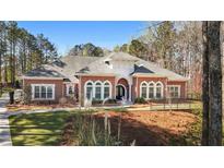 Charming red brick home with arched windows, manicured lawn, and lush landscaping for enhanced curb appeal at 850 Cog Hl, Mcdonough, GA 30253