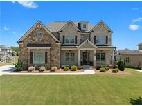 Stately brick home with a manicured lawn, charming shutters, and a welcoming front porch at 4800 Gablestone Xing, Hoschton, GA 30548