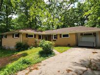 Charming single-story brick home featuring a covered parking area and surrounded by lush greenery and mature trees at 1321 Snapfinger Rd, Decatur, GA 30032