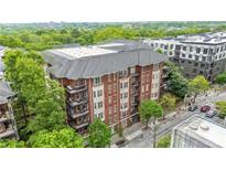 Charming brick condo building with a gray roof and multiple balconies surrounded by lush green trees at 850 Piedmont Ne Ave # 1409, Atlanta, GA 30308