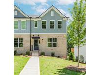Charming townhome with a brick facade, manicured lawn, and inviting entrance with black door and awning at 1230 Ainsworth Aly # 34, Sugar Hill, GA 30518