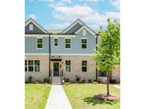Charming townhome featuring a brick facade, well-manicured lawn, and inviting entryway at 1242 Ainsworth Aly # 40, Sugar Hill, GA 30518