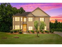 Inviting two-story home with manicured lawn, mature trees, and colorful sunset sky at 279 Sturry Dr, Mcdonough, GA 30252