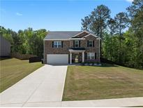 Charming two-story brick home features an attached two-car garage and a well-maintained front lawn at 435 Noblewood Dr, Mcdonough, GA 30252